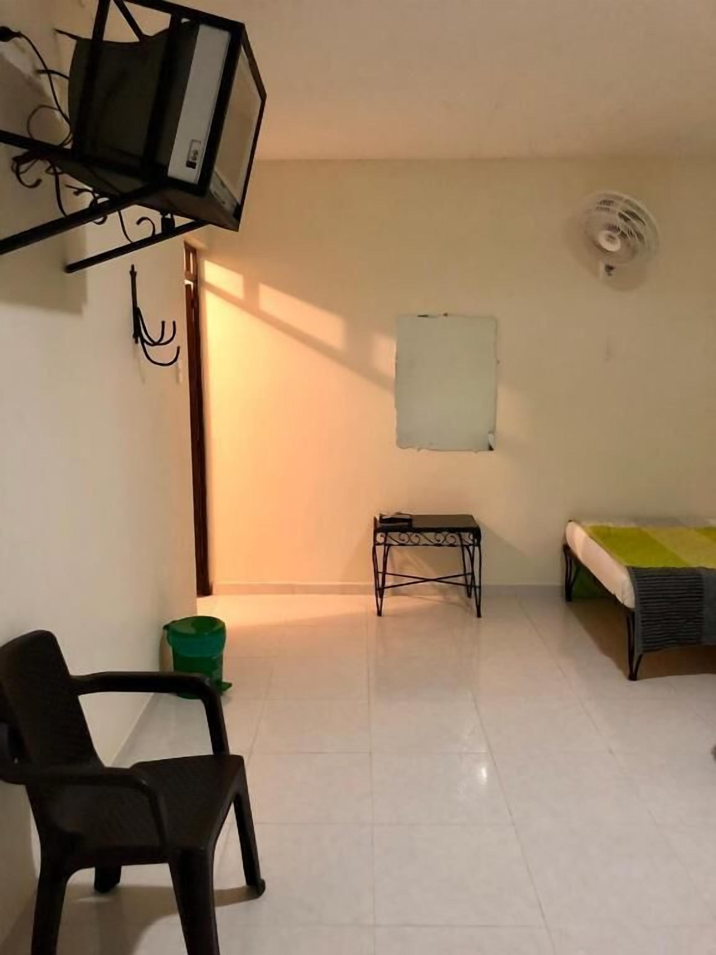 Una habitación con una cama, una mesita, una silla, un televisor y un aire acondicionado instalado en la pared.