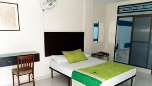 Une chambre à coucher comprenant un lit, un bureau, une chaise, une table de chevet et une fenêtre.