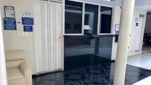 Un espace d’accueil avec un canapé beige, un sol à motifs noir et blanc et une porte blanche dotée d’une fenêtre.