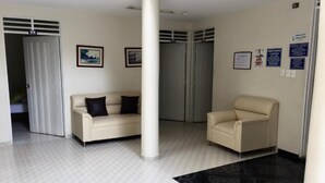Un espace d’accueil avec deux canapés, une colonne et un tapis à motifs.