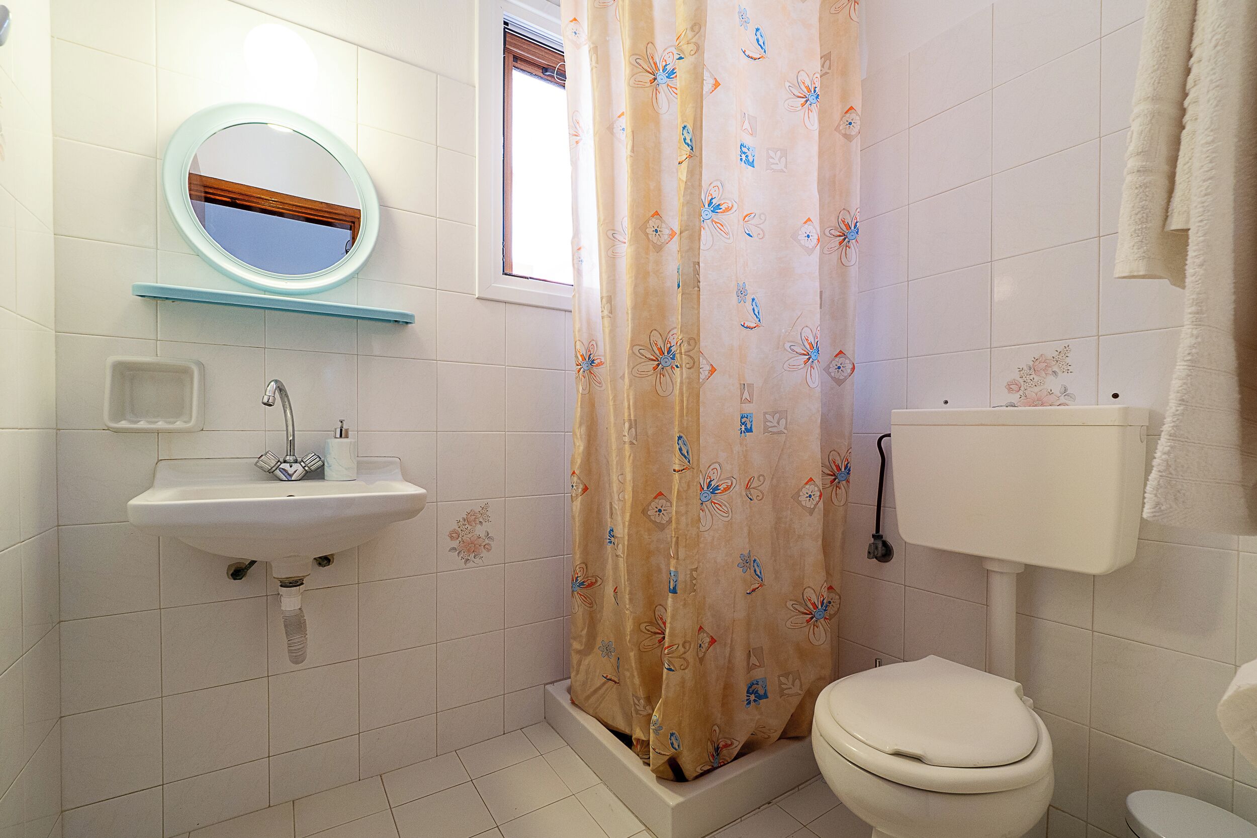 A bathroom with a sink, mirror, toilet, and shower curtain.
