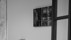 A minimalist bedroom with a bed, pillows, a wall-mounted light, and a door frame. - Xenofontas apartments (Corfu)