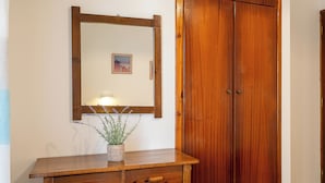 A wooden wardrobe with two doors, a wooden bedside table with a drawer, and a mirror above the table. - Xenofontas apartments (Corfu)