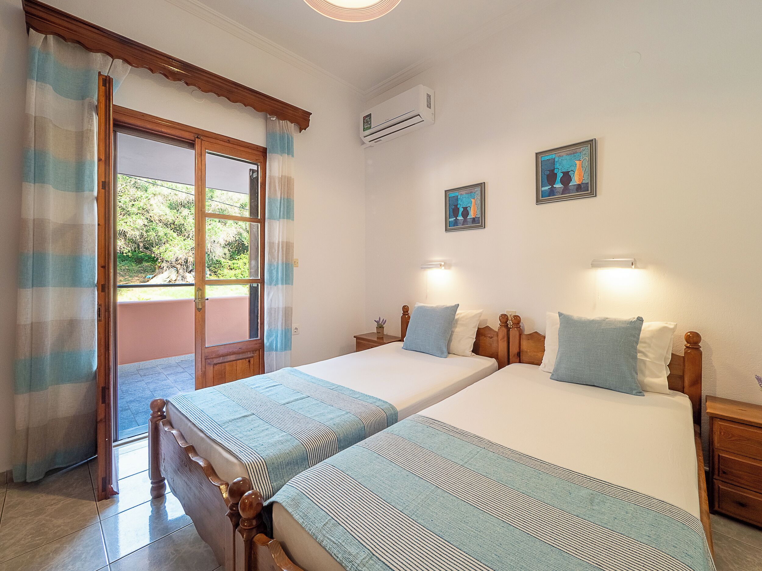 A double room with two beds, a balcony, and an air conditioning unit.