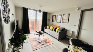 Ein modernes Wohnzimmer mit einem grauen Sofa, einem Couchtisch und einem großen Fenster.