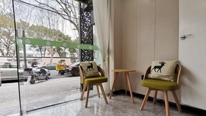 A hotel lobby with two green cushioned chairs with deer motifs, a small wooden table, and a glass door leading outside. - Shanghai Jinrui Hotei （Linyi Road ） (Shanghai)