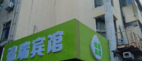 A building with a green sign that reads 'Hotel'.