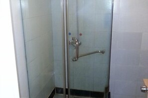 Une cabine de douche fermée par des parois en verre, équipée d’une barre d’appui et d’un pommeau de douche.