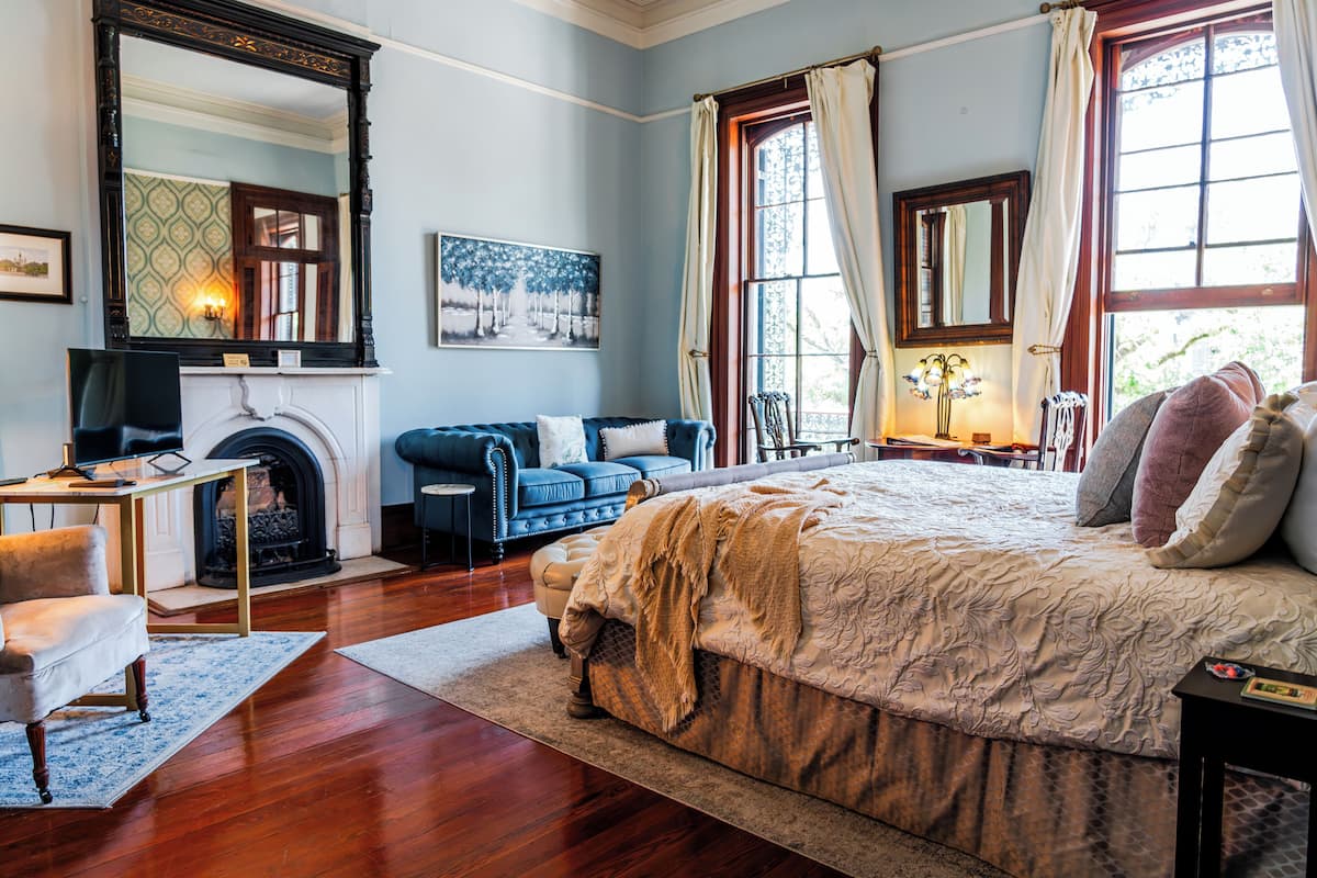 Un dormitorio con una cama grande, una chimenea, un sofá azul y una mesa de comedor.