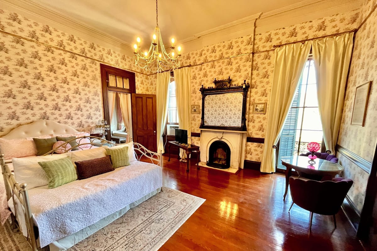 Una habitación tradicional con cama, chimenea y candelabro.