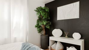 A bedroom with a bed, a large potted plant, a white console table, and a black accent wall. - Prestine Pet Friendly Home near Ontario Airport- Convection Center  (Ontario)