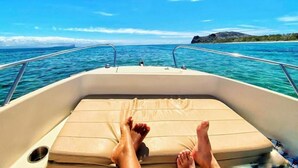 A boat with a cushioned deck and metal railings, viewed from the bow. - Laurels Villas (Pereybere)