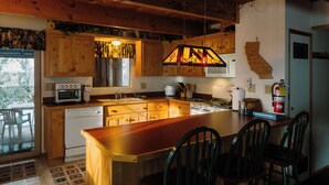Une cuisine avec des meubles en bois, un îlot central et un luminaire suspendu.