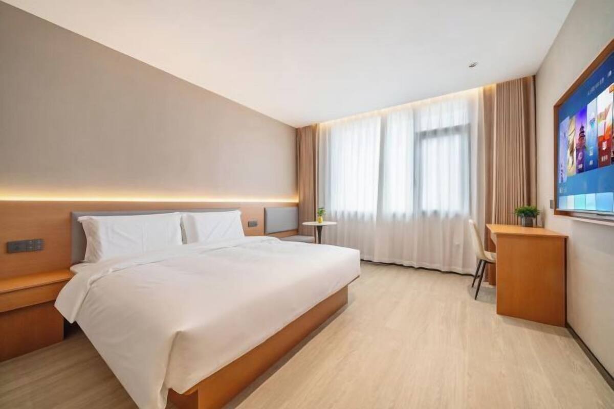 A hotel room with a large bed, bedside tables, a desk, and a TV.