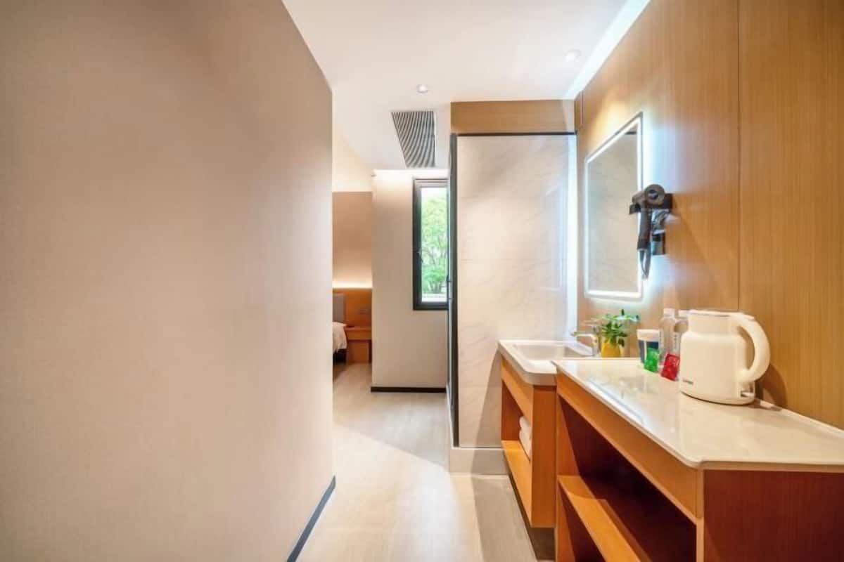 A modern bathroom with a wooden vanity, a mirror, and a sink.