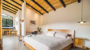 A bedroom with a wooden bed, bedside tables, a desk, and chairs.