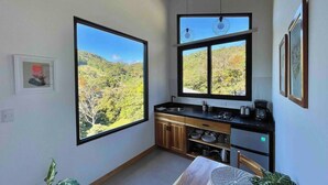 A compact kitchen with large windows, a dining table, and a view of a mountainous landscape.