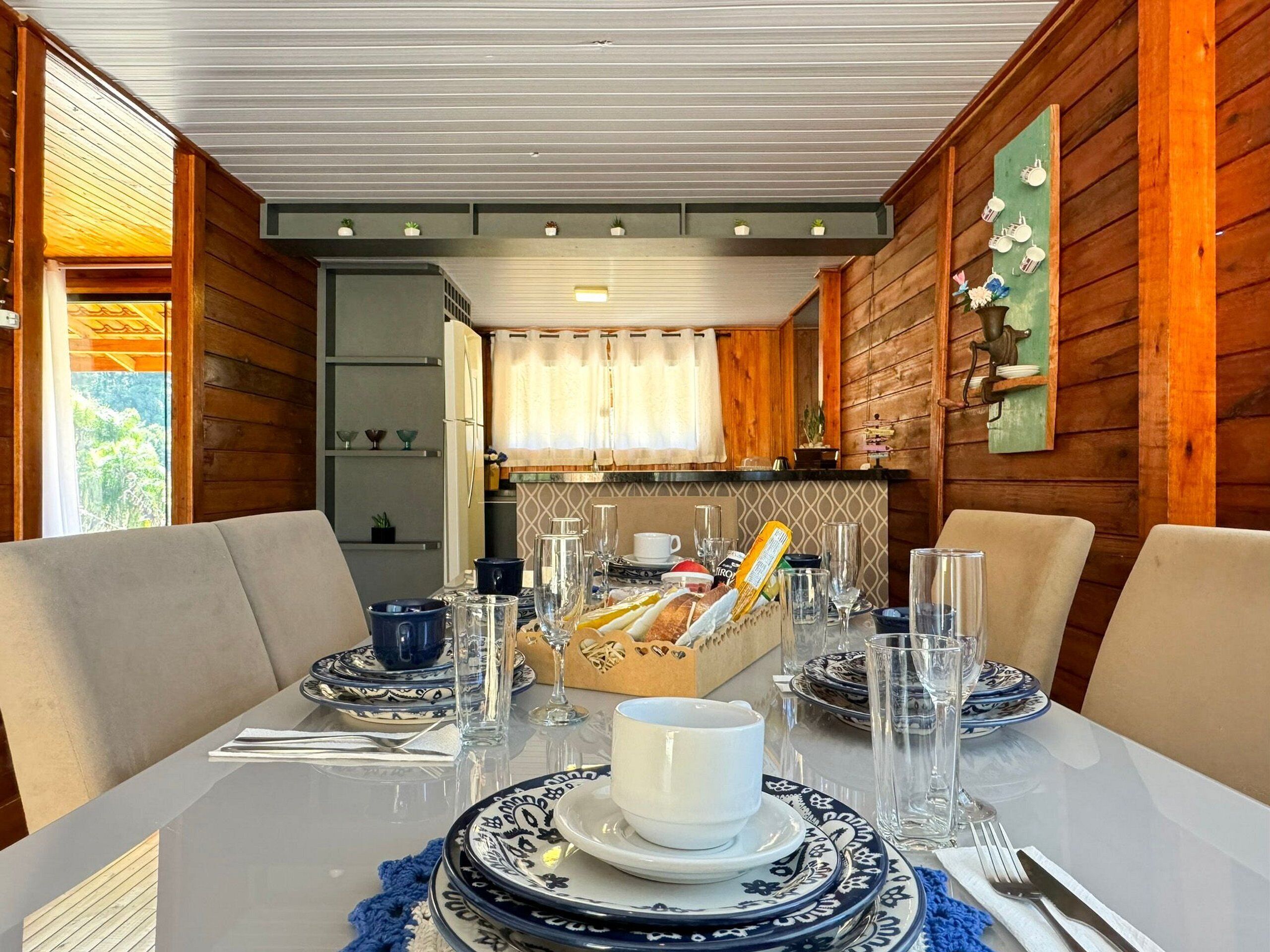 Un coin repas avec une table dressée pour deux personnes, agrémentée d’une nappe blanche, d’assiettes à motifs bleus et blancs, et de verres transparents.