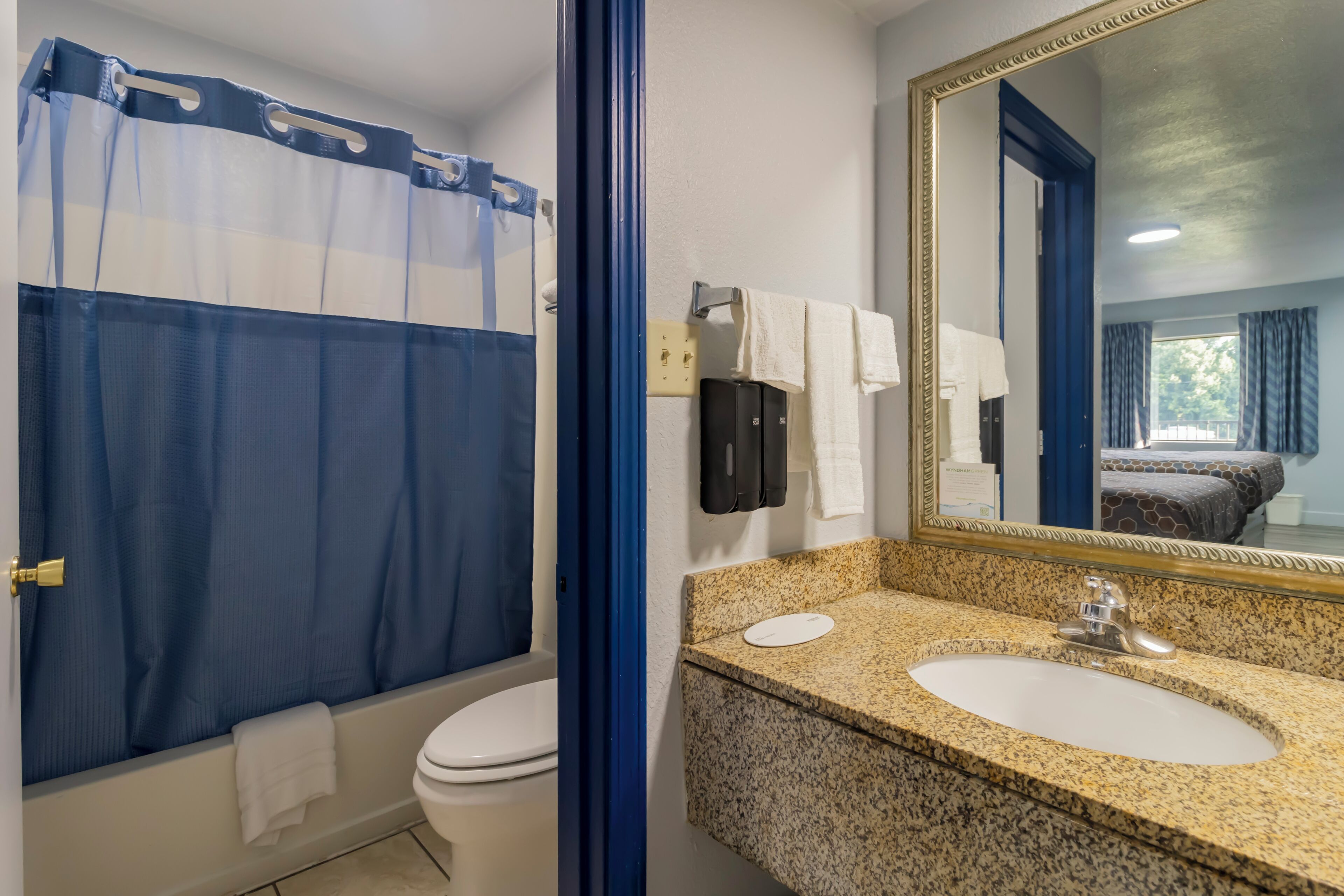 Une salle de bain avec un rideau de douche, des toilettes, un lavabo avec un miroir et un porte-serviettes.
