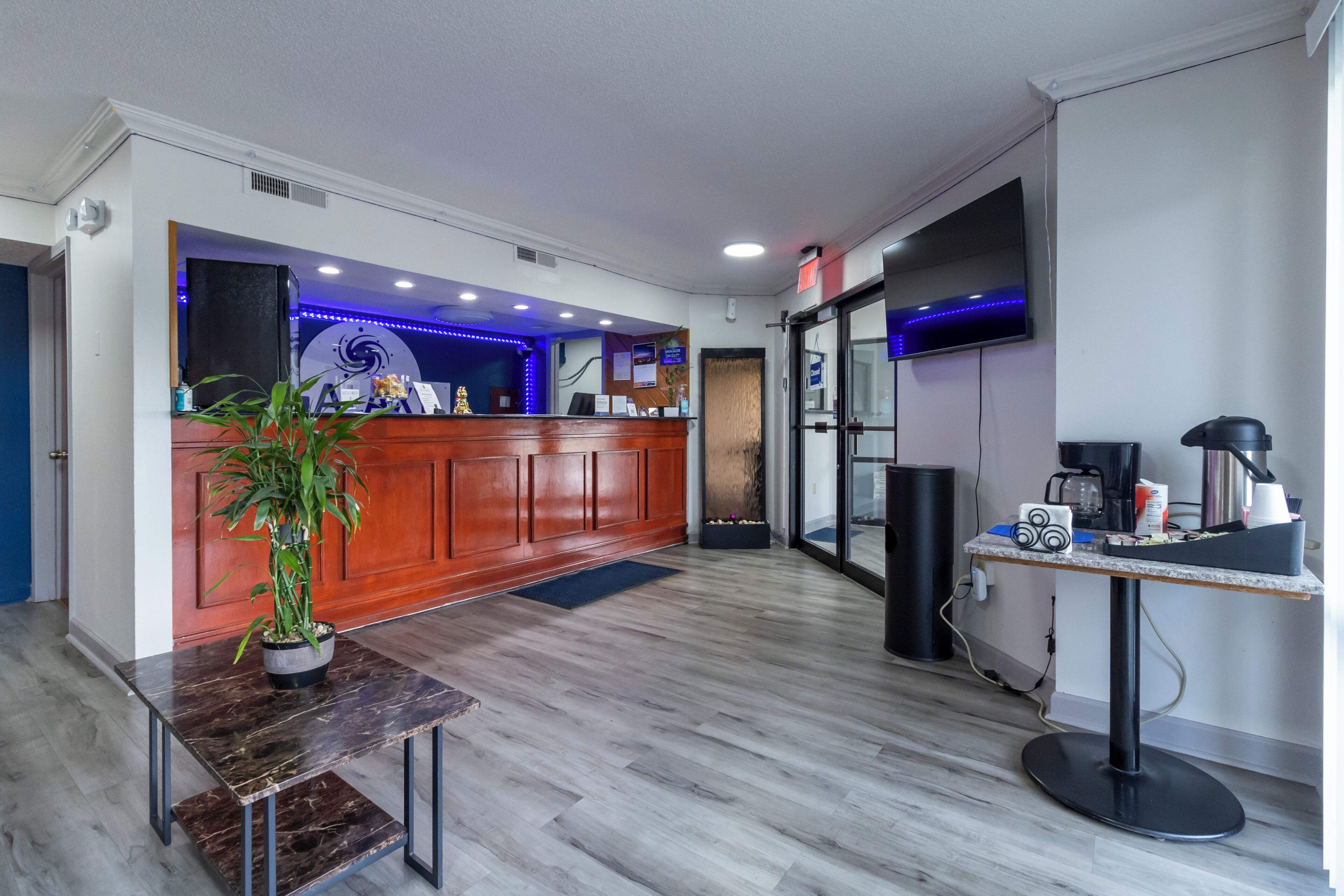 A reception area with a wooden desk, a potted plant, and a reception desk with a blue accent wall.