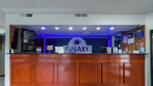 A Galaxy Inn & Suites reception desk with a sign, a refrigerator, and a water dispenser.