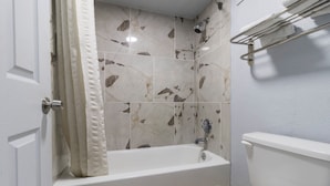 A bathroom with a bathtub, a toilet, and a shower.