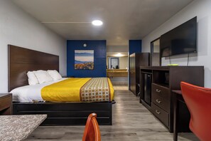Hotellihuone, jossa on sänky, työpöytä, televisio ja taustalla näkyvä kylpyhuone.