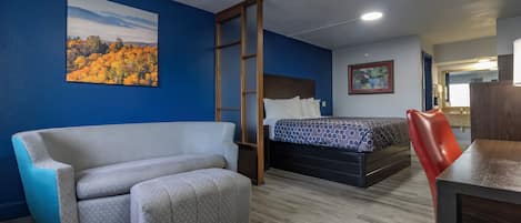 A hotel room with a sofa, a bed, a desk, and a chair.