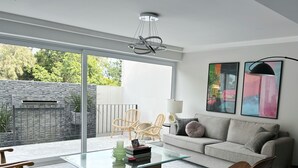 Una sala moderna con una mesa de centro de cristal, un sofá gris y dos sillas de madera.