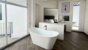 Un baño moderno con una bañera independiente, un ventanal grande y un balcón.