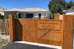 A wooden gate with a sign indicating a modern house with a pool. - Modern house with a pool, nestled between the lake and the forest (Lacanau)