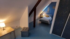 A bedroom with a bed, a nightstand, a lamp, and a small stool.