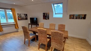 Ein Essbereich mit Holztisch und Korbstühlen, einem Fernseher und Kunstwerken an den Wänden.