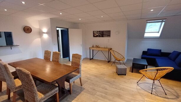 Ein modernes Wohnzimmer mit einem Holzespeisetisch, Korbstühlen, einem blauen Sofa und einem kleinen Tisch mit Dekoration.