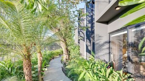A pathway flanked by lush greenery and modern architecture.