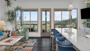 A modern kitchen with a bar area, large windows, and a view of the outdoors.