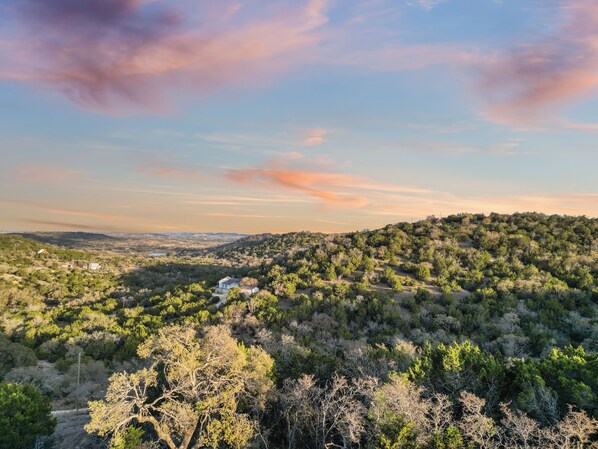 A mountainous landscape with a house surrounded by dense forest.