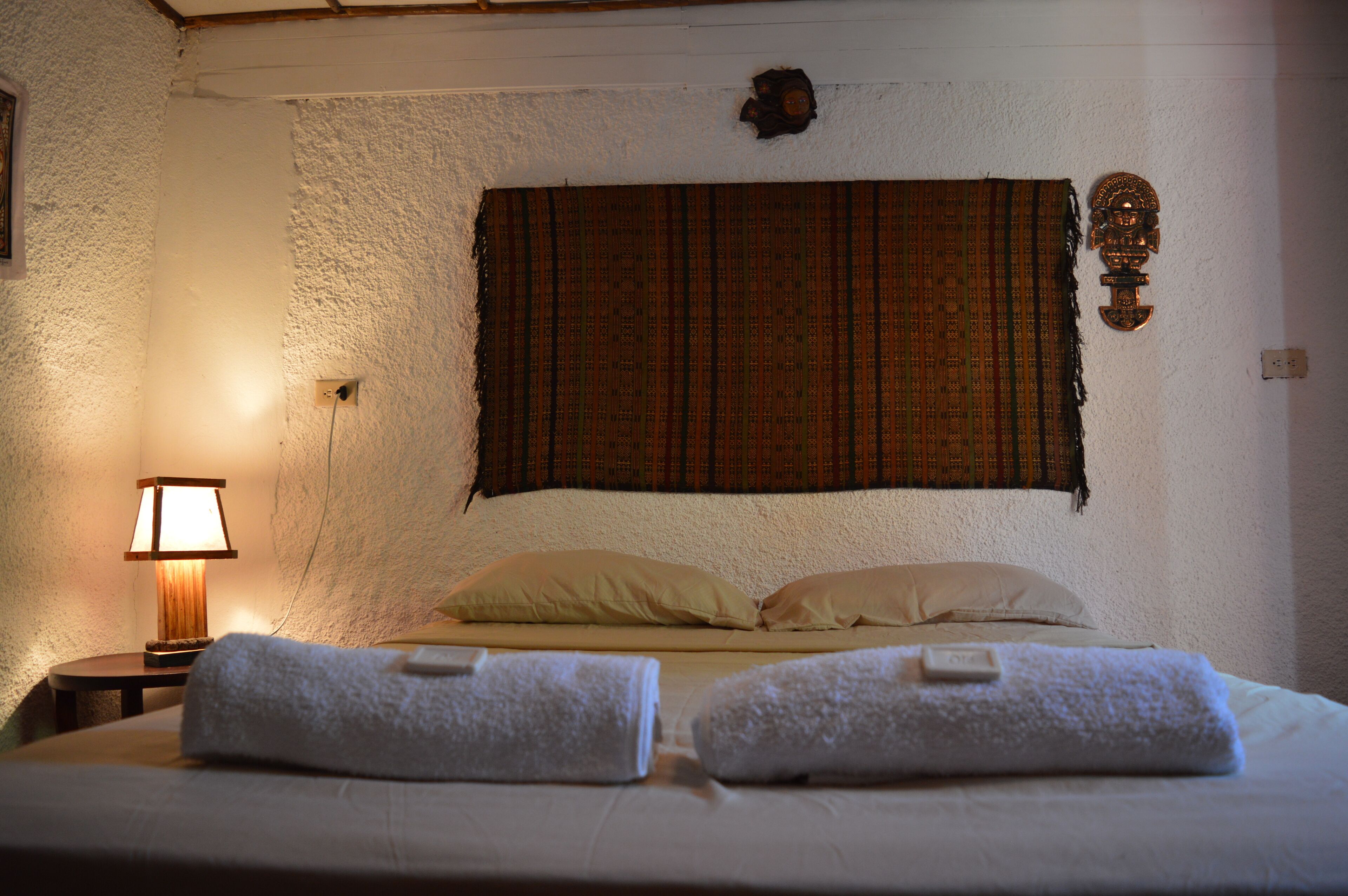 Une chambre d’hôtel avec un lit, deux oreillers, une couverture, une lampe et un tableau ou une décoration murale.