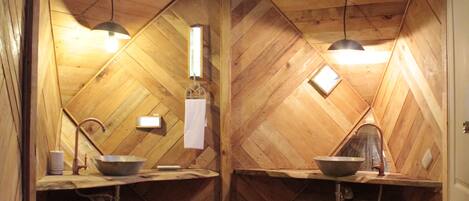 A wooden attic bedroom with a sloped ceiling, two wooden beds, a small window, and a wooden floor.