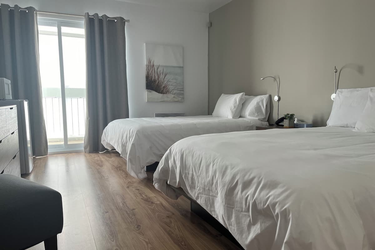 Ein Hotelzimmer mit zwei Betten, einem Schreibtisch und Blick ins Freie.