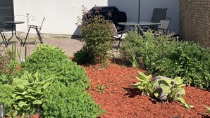 An outdoor patio with a grill, seating, and a small garden area. - HĂ´tel Normandie (Rimouski)