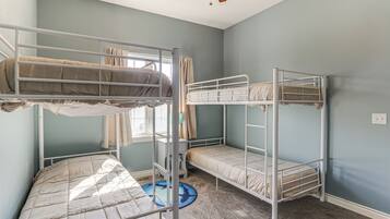 Une chambre avec des lits superposés, un ventilateur de plafond et une fenêtre avec des rideaux.