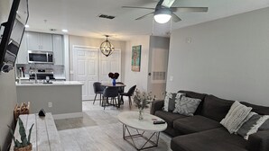 A modern living room with a dark brown sofa, a white coffee table, and a dining area with a white table and chairs.