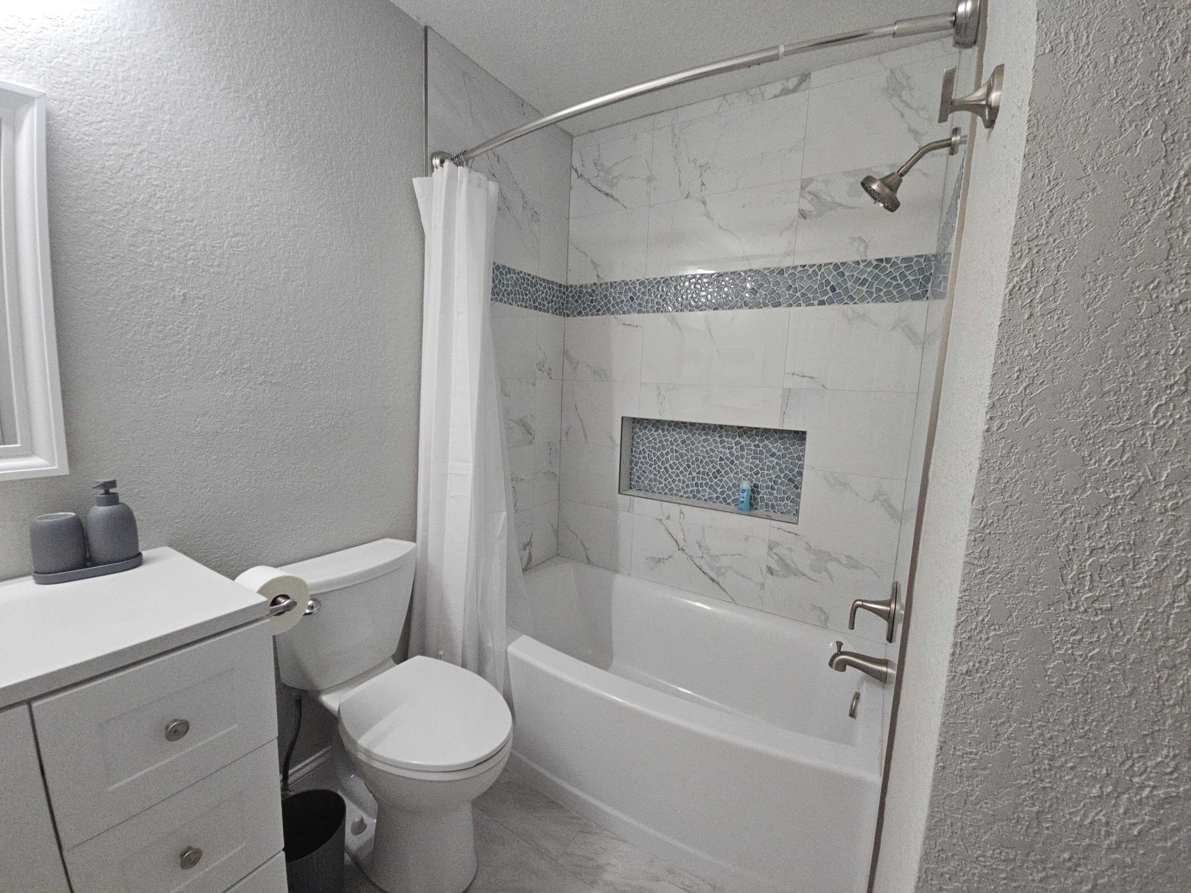 A bathroom with a toilet, a shower with a glass door, and a bathtub.