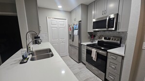 A modern kitchen with stainless steel appliances, a white countertop, and a double sink.