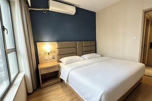 Una habitación de hotel con cama, mesita de noche, lámpara y ventana.