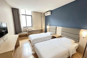 Hotellihuone, jossa on kaksi sänkyä, työpöytä, televisio ja ikkuna.