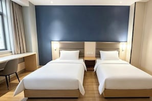 Hotellihuone, jossa on kaksi sänkyä, työpöytä ja näkymä kaupunkiin.