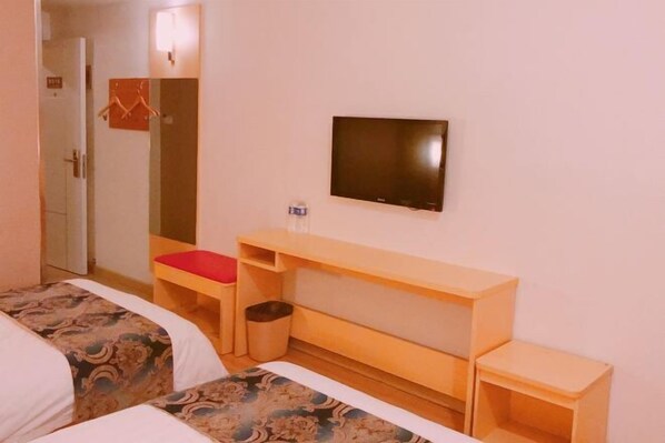 Habitación de hotel con dos camas, televisor, una mesita y un espejo.