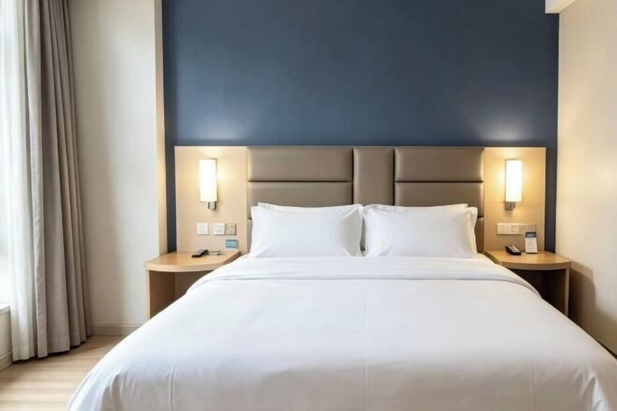 Une chambre d’hôtel avec un grand lit, deux tables de chevet et une tête de lit dotée d’un éclairage intégré.